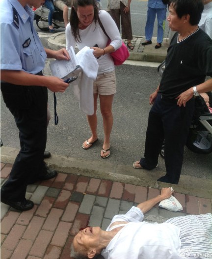 老人晕倒街头,外国女子给其头下垫毛巾。(来源:网络)