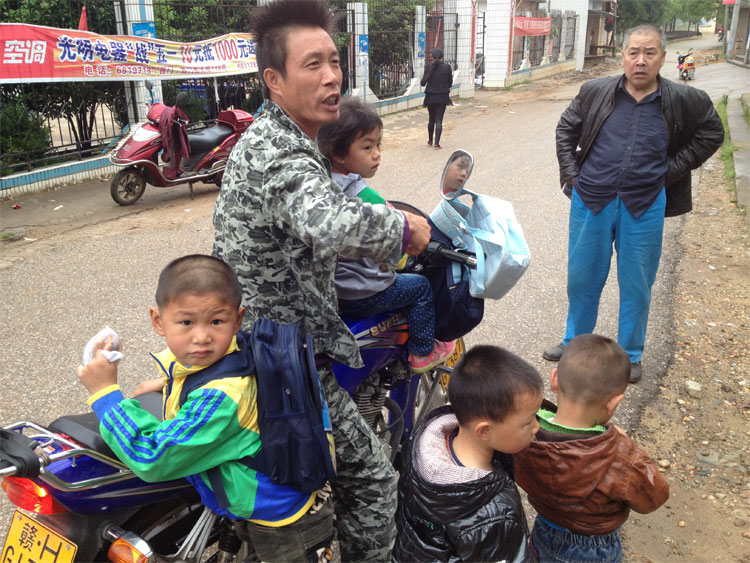 孩子们没有校车坐,村民只能自己接送,一辆摩托车载4个小孩。