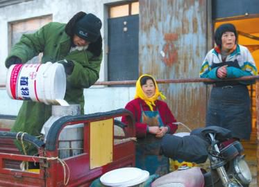 1月10日,在北京市延庆县大榆树下辛庄村村头奶站,工作人员在将一桶鲜奶出售。新华社发