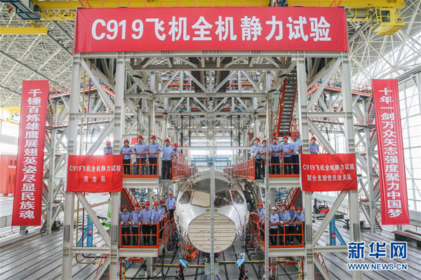 　　在位于上海浦东机场区域的中国航空工业飞机强度研究所内，工作人员在C919大型客机10001验证飞机的工作平台上合影（6月21日摄）。新华社记者 丁汀 摄