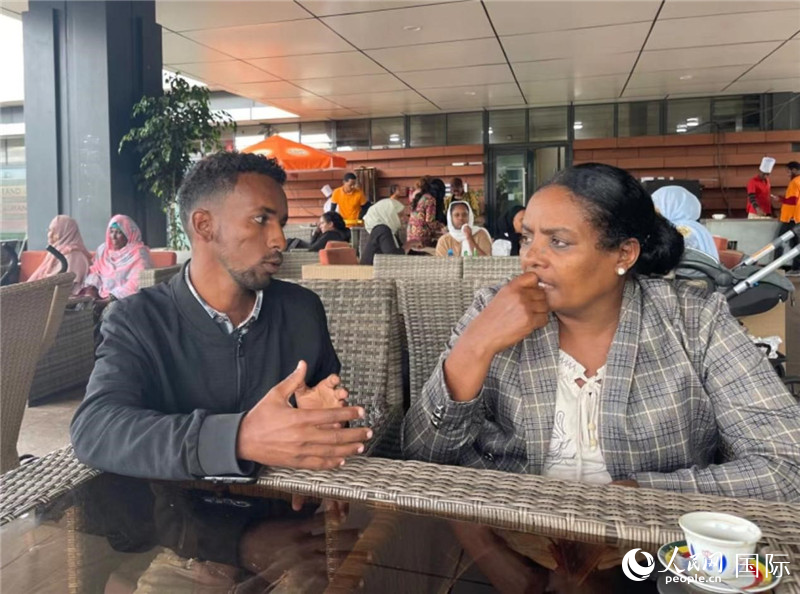 约汉斯(图左)与德贝拉在友谊广场咖啡厅交谈。人民网记者 赵艳红摄