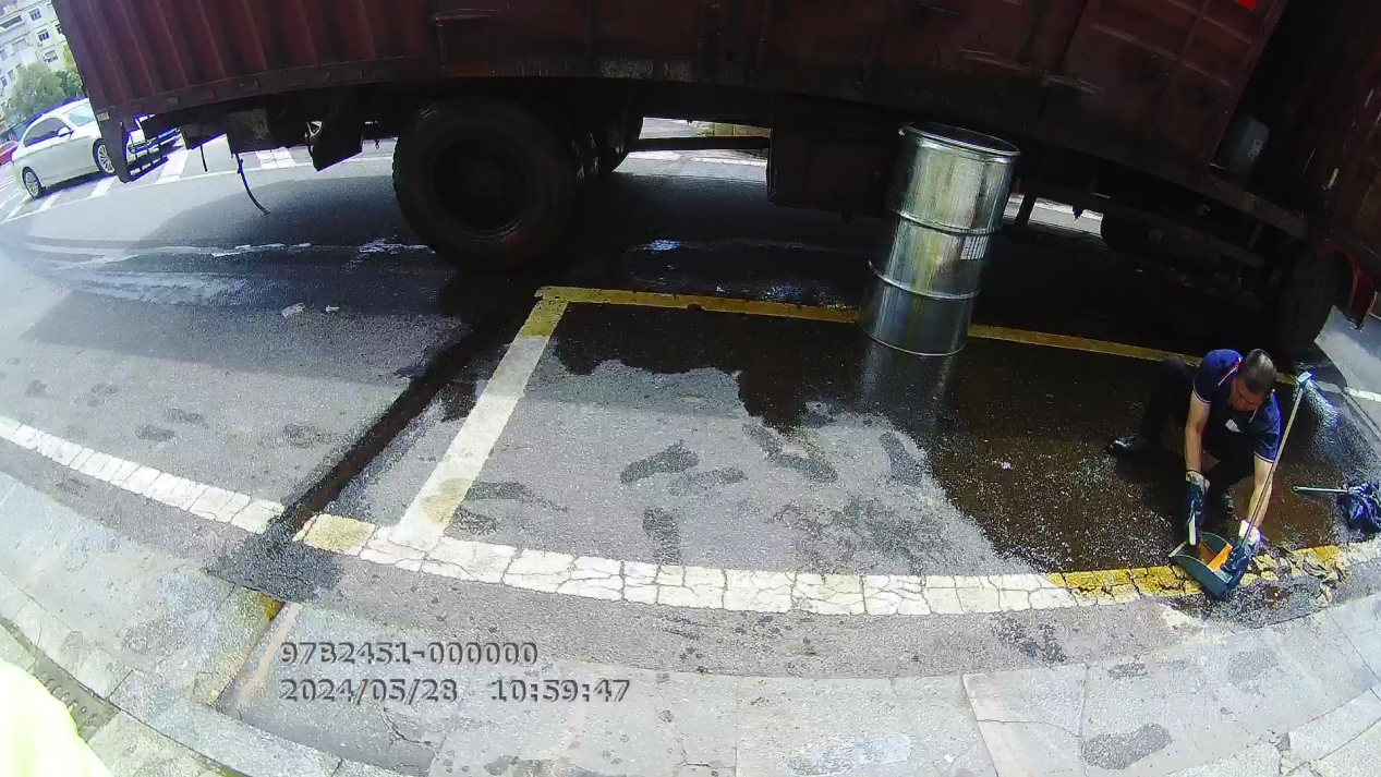 一男子在用抹布擦拭路口的油渍