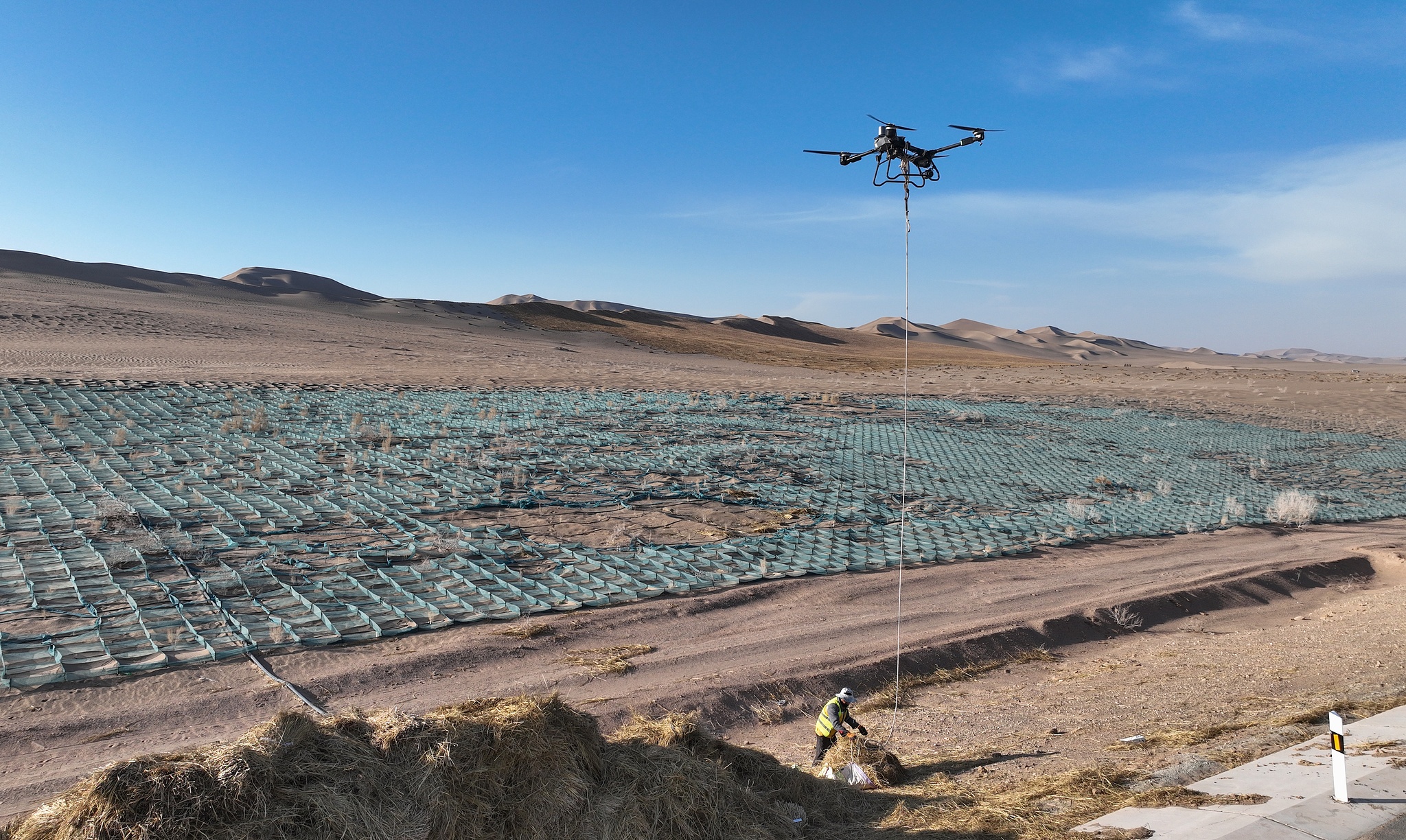 A drone transports grass in desert, Jiuquan City, Gansu Province, northwest China, December 3, 2024. 