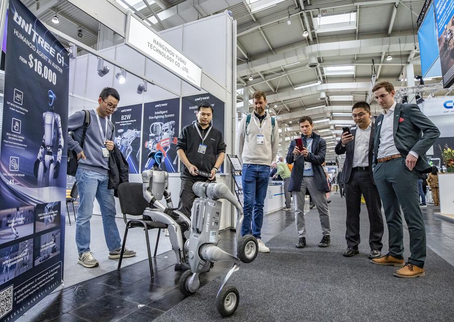 Visitors watch a robot performing at the exhibition booth of Unitree at Hannover Messe 2025 in Hannover, Germany, on April 1, 2025. (Xinhua/Zhang Fan)