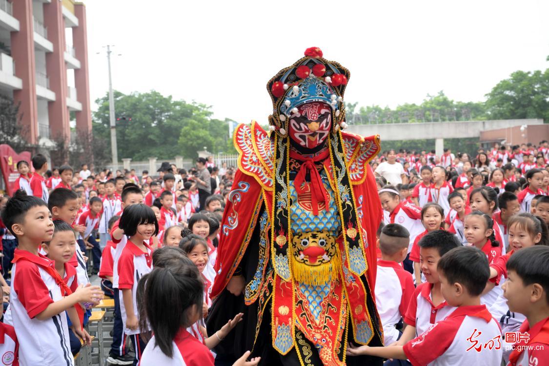 湖南省资兴市文化馆组织衡州花鼓戏演员走进校园,通过示范、教学及邀请学生现场体验等方式,让学生们近距离接触传统戏曲文化,感受非遗的独特魅力。图为演员在资兴市第四完全小学表演川剧变脸。(何洪海摄/光明图片)