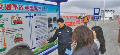青海省茫崖市公安局民警于一亮在冷湖镇苏干湖执勤卡点，向停车休息的游客宣讲道路交通安全知识。