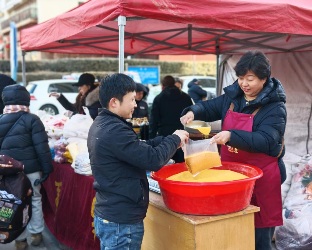 2月11日，尤变清（右）在太原市区销售点推销南留南村特色农产品。